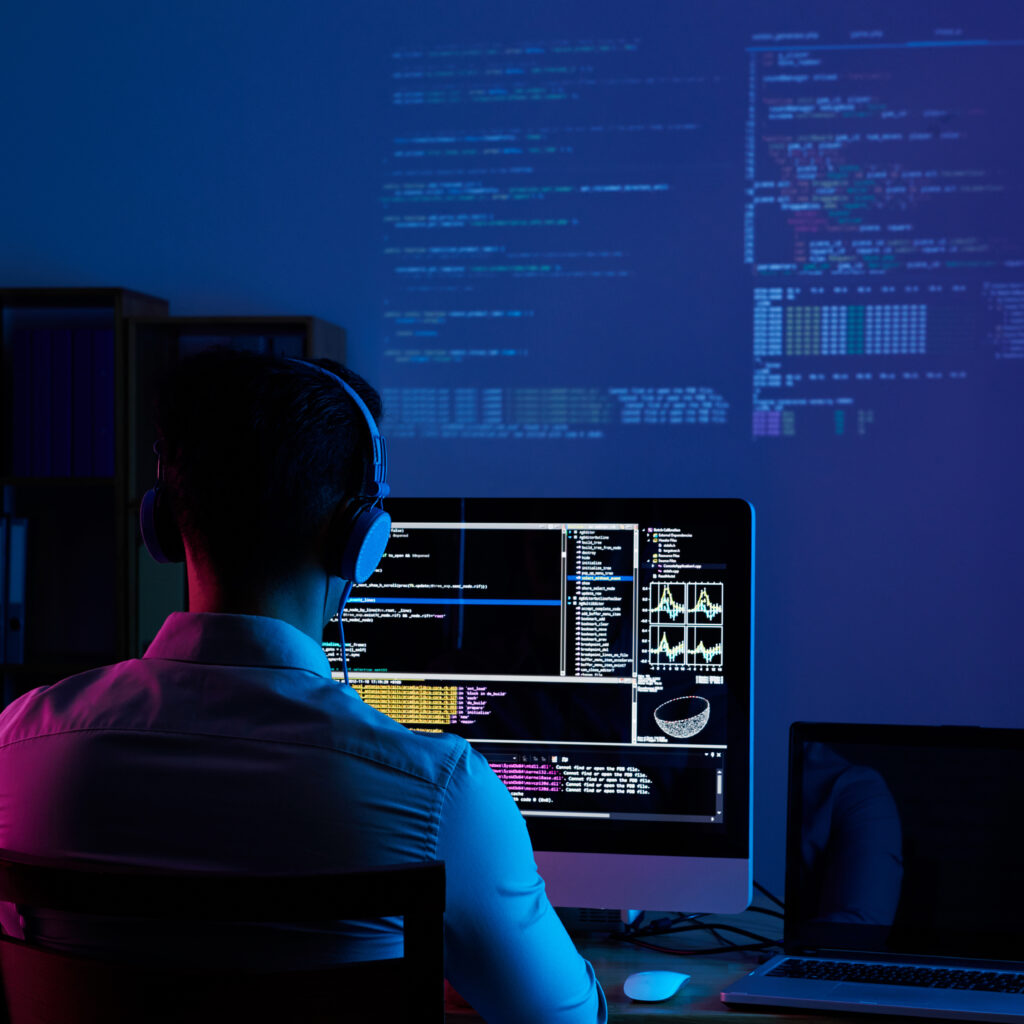 Developer working on code late at night, view from the back
